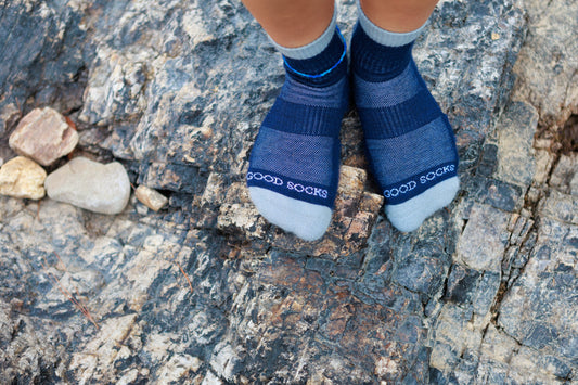Person wearing merino wool socks from Good Socks while standing on a boulder—showcasing rugged durability, outdoor performance, and the importance of proper sock care for long-lasting wear.